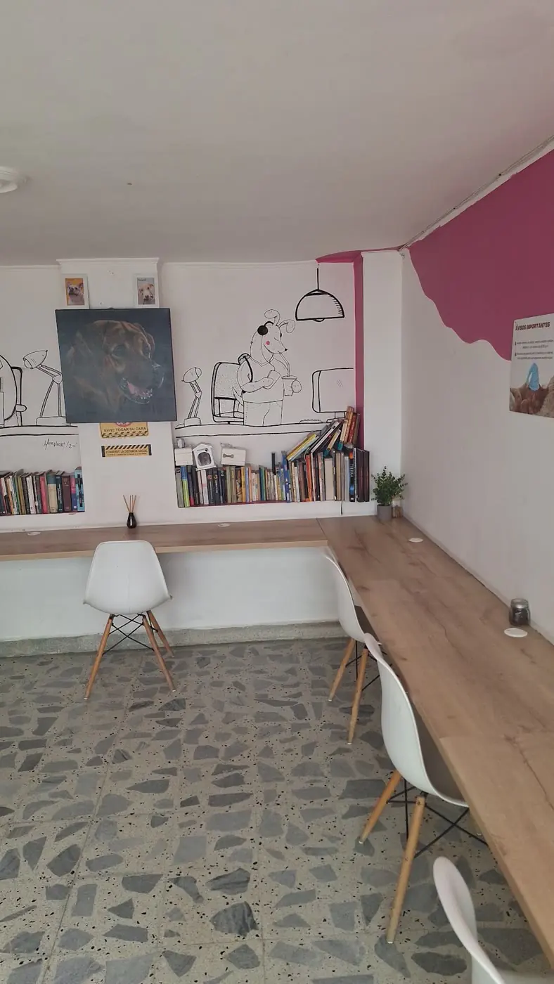 Sala de coworking de Café Fundación con mesa larga, sillas blancas y biblioteca